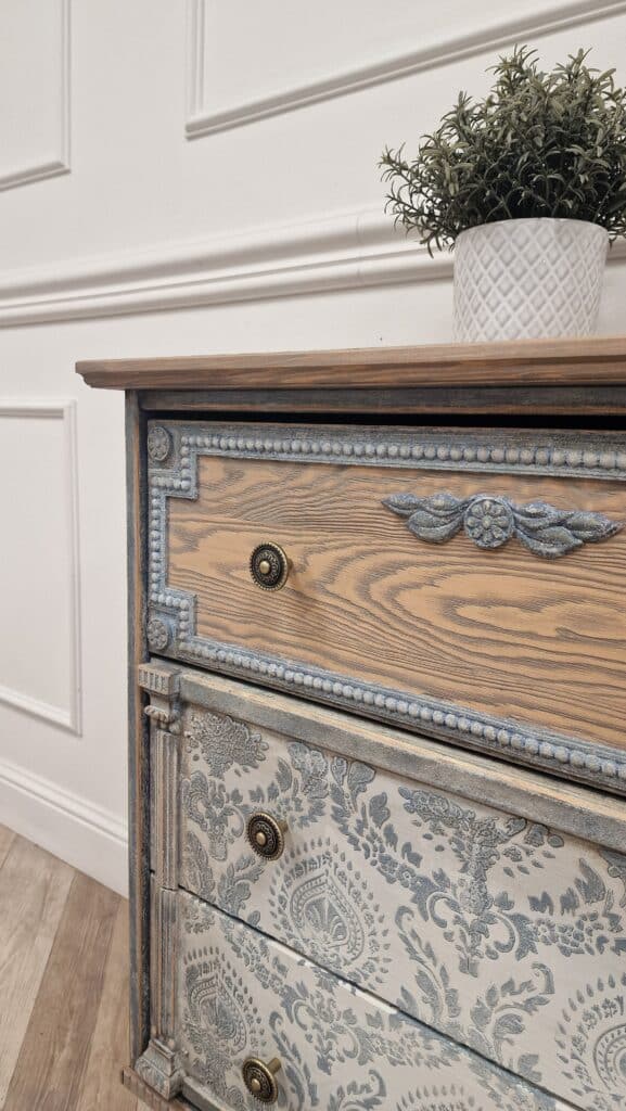 Zbliżenie na szuflady komody w stylu French Vintage, z ozdobnym wzorem i stylizowanymi uchwytami.