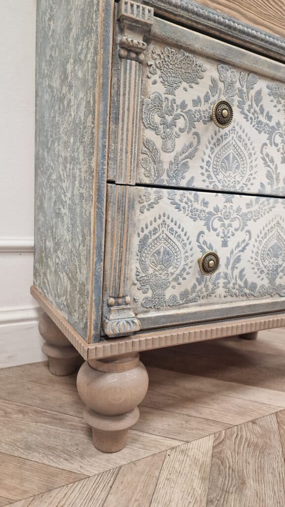 Detal rzeźbionej nogi i dekoracyjnych elementów komody w stylu French Vintage, z efektem postarzania.
