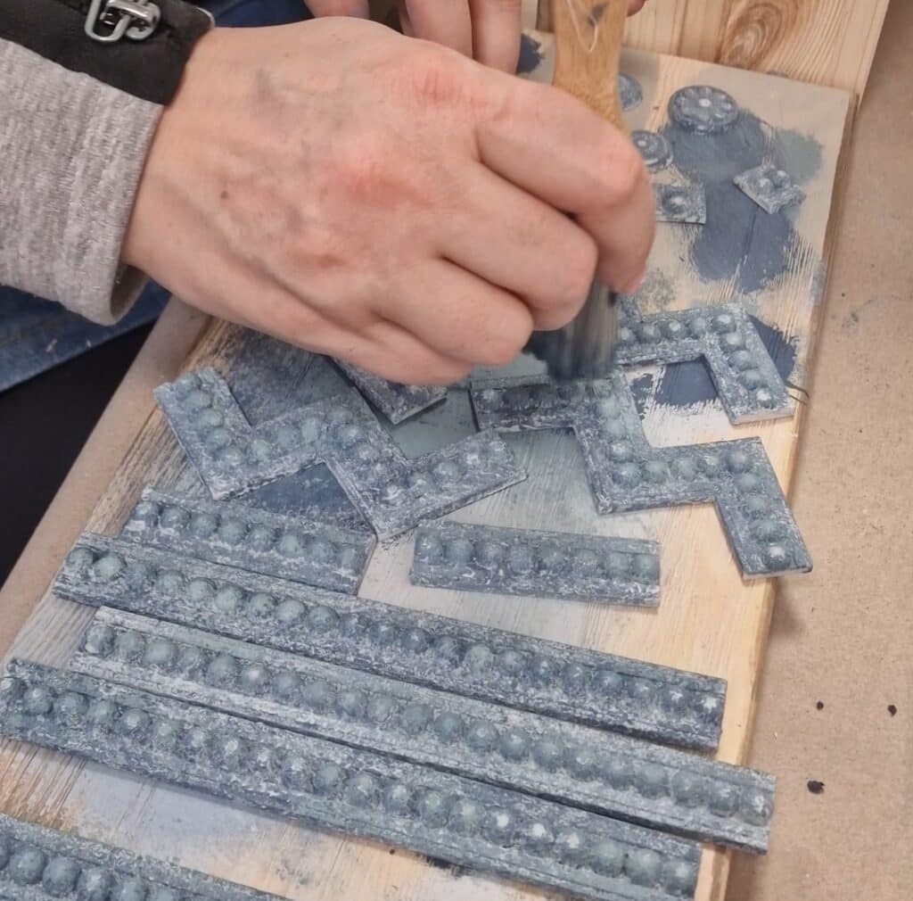 Ręczne malowanie ozdobnych listew z żywicy do komody w stylu French Vintage, tworzenie detali stylizacyjnych.