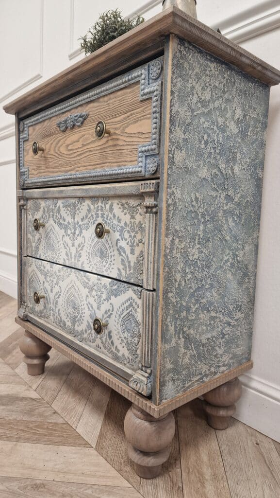 Ozdobne rzeźbienia na frontach szuflad komody w stylu French Vintage, z efektem patyny.